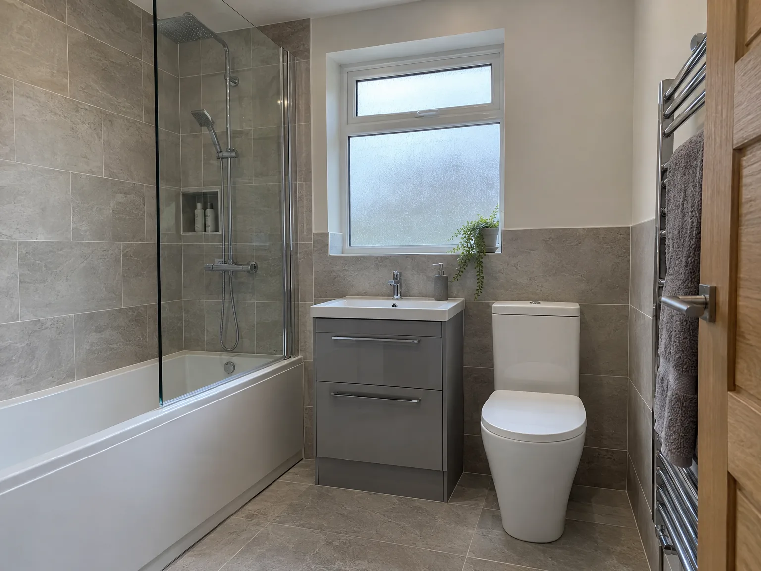 Modern bathroom with slate-effect tiles, walk-in shower, grey vanity unit, white toilet and heated towel rail