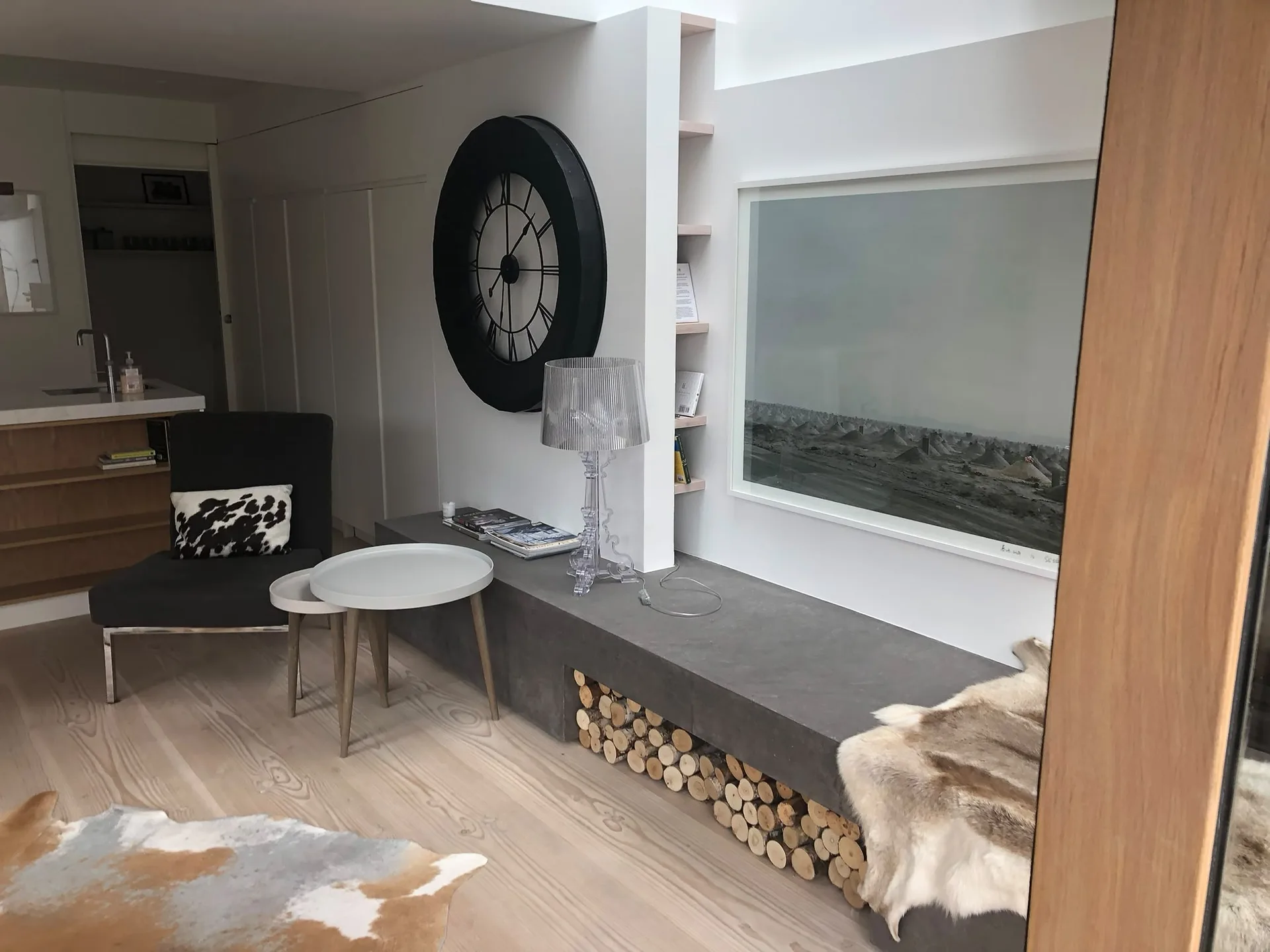 Modern living room interior with custom-built fireplace, designer seating, and contemporary furnishings on light wood flooring