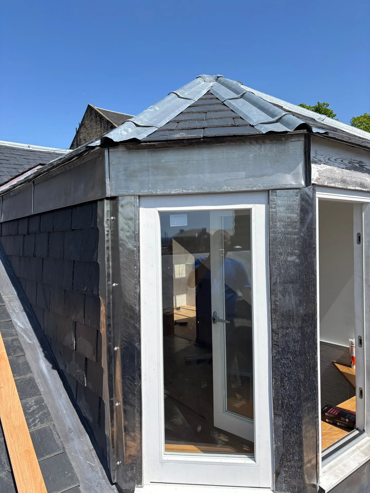 Modern garden room with dark slate roof, white glazed patio doors, and charcoal timber cladding