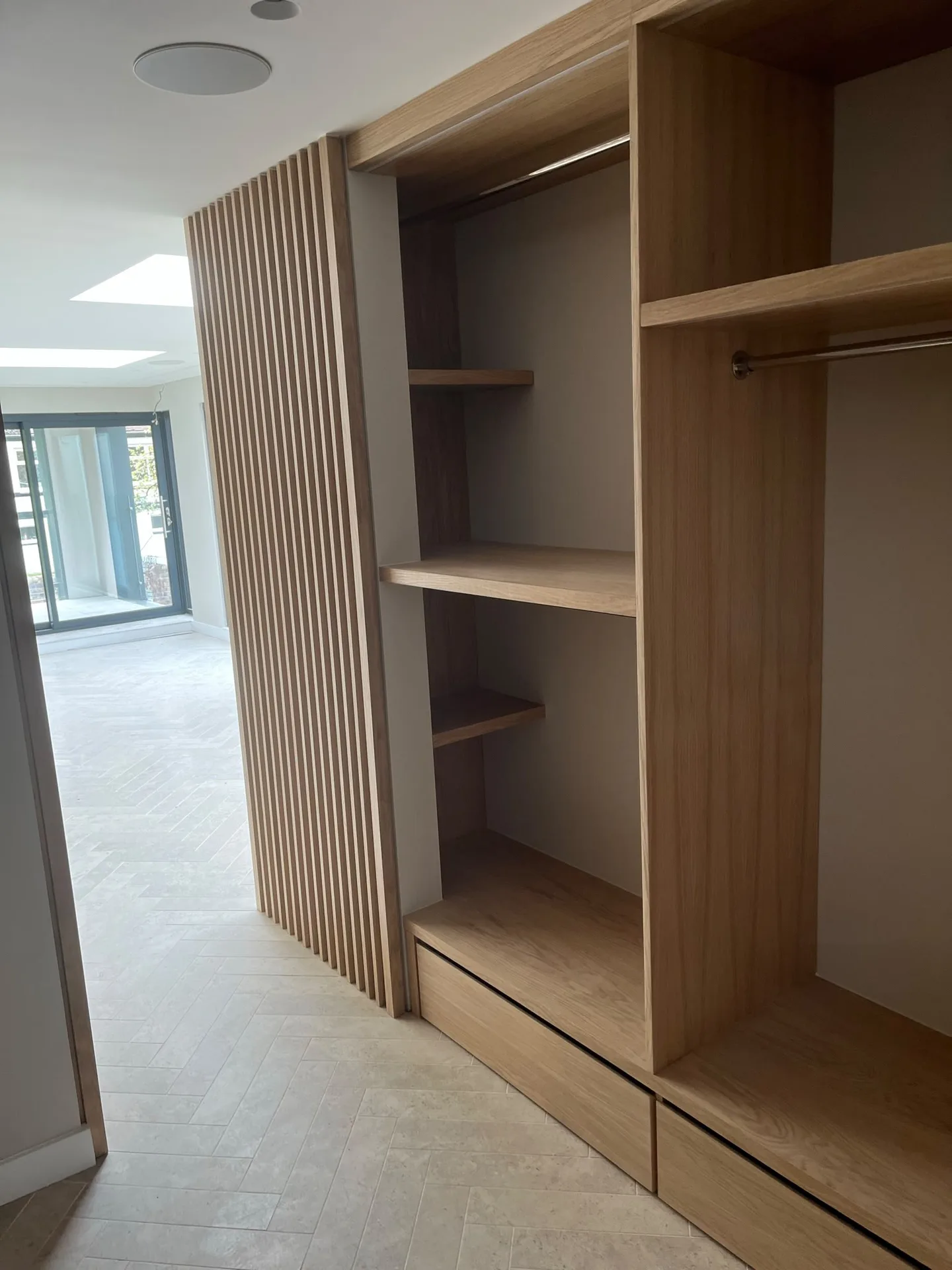 Modern fitted wardrobe with vertical timber slats and integrated open shelving in contemporary home interior