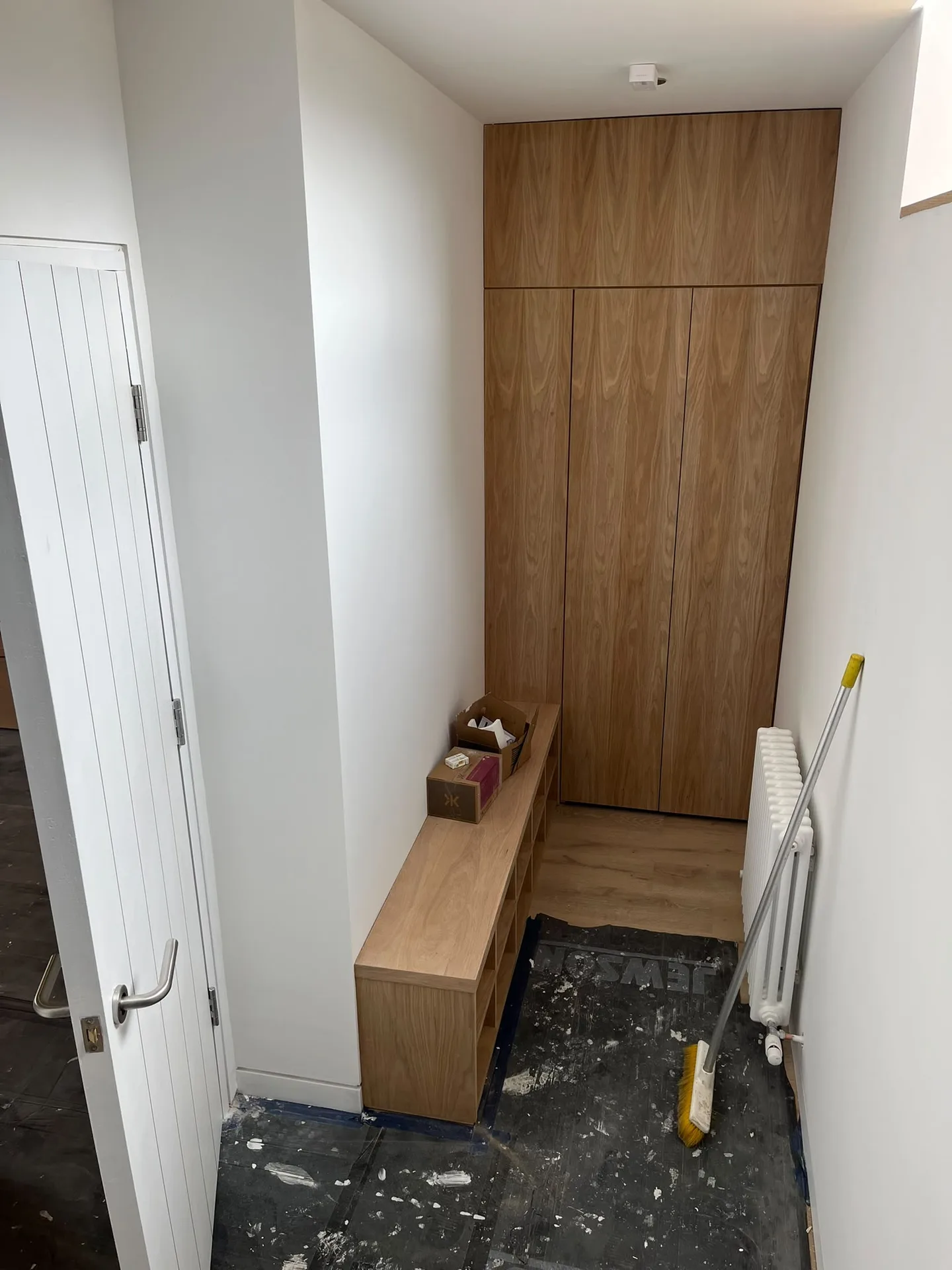 Bespoke wooden wardrobe cabinet with integrated bench seating in contemporary hallway interior fit out
