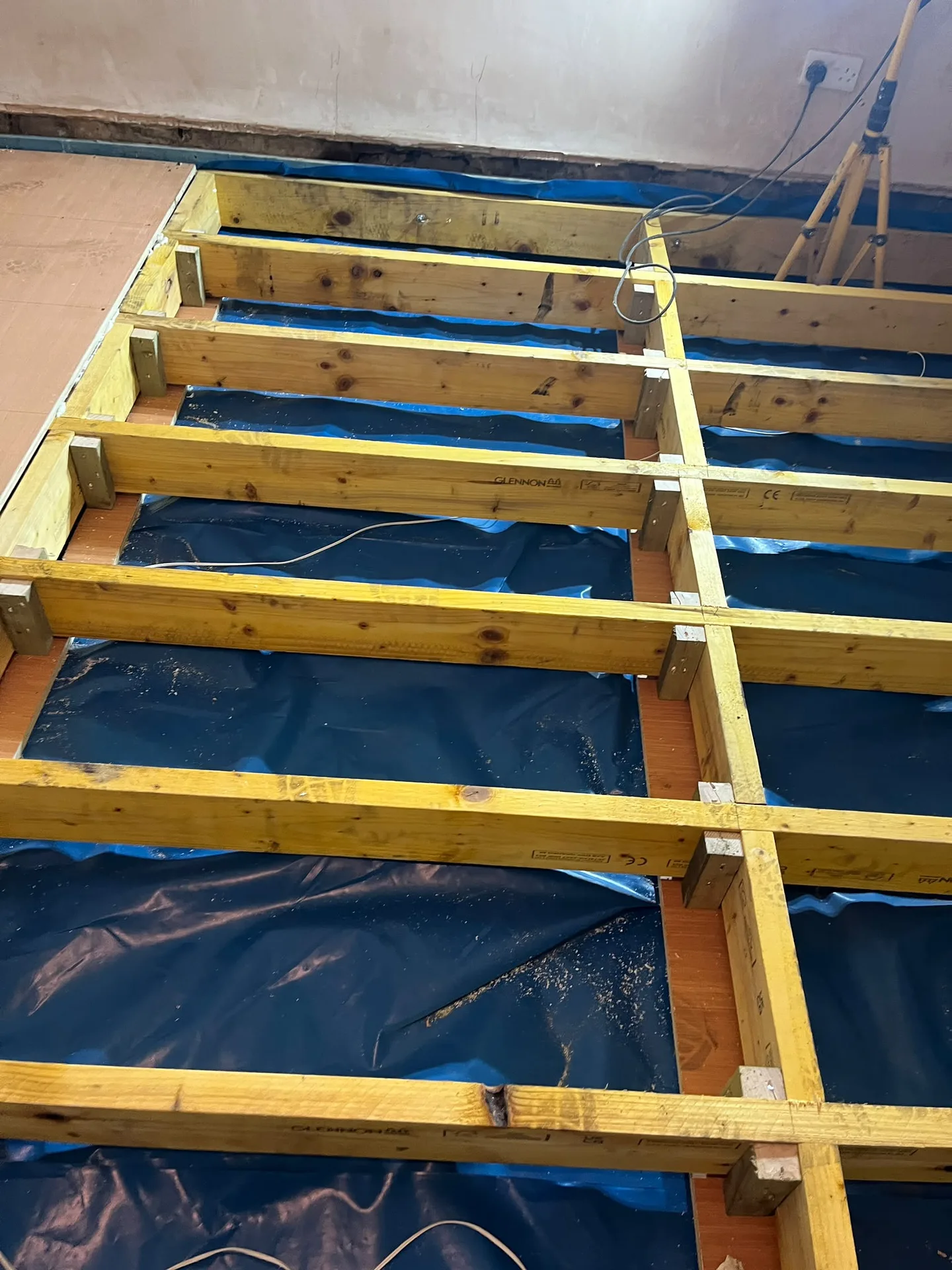 Wooden structural joists with protective blue sheeting during house construction or renovation phase