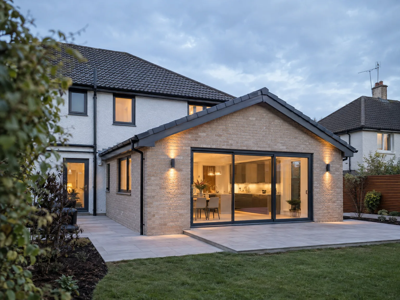 Modern brick house extension with large glazed bifold doors and illuminated patio
