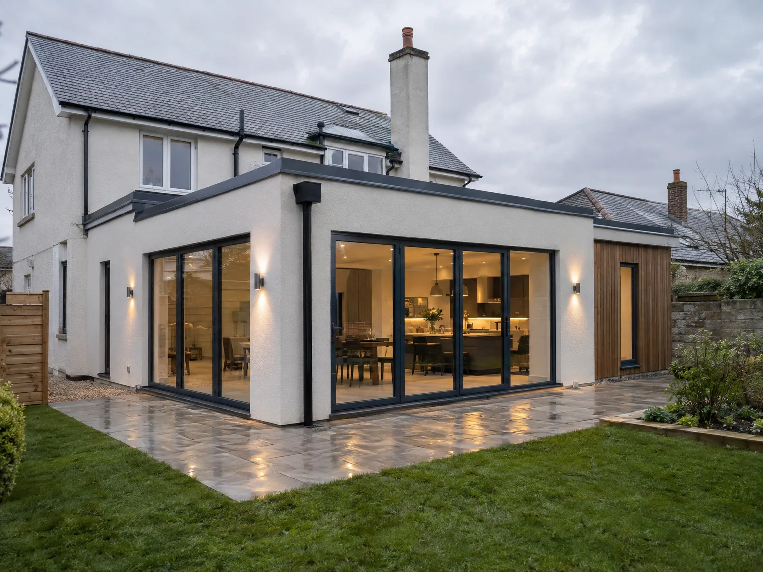 Contemporary house extension with black-framed sliding doors, professional stone patio, and integrated lighting