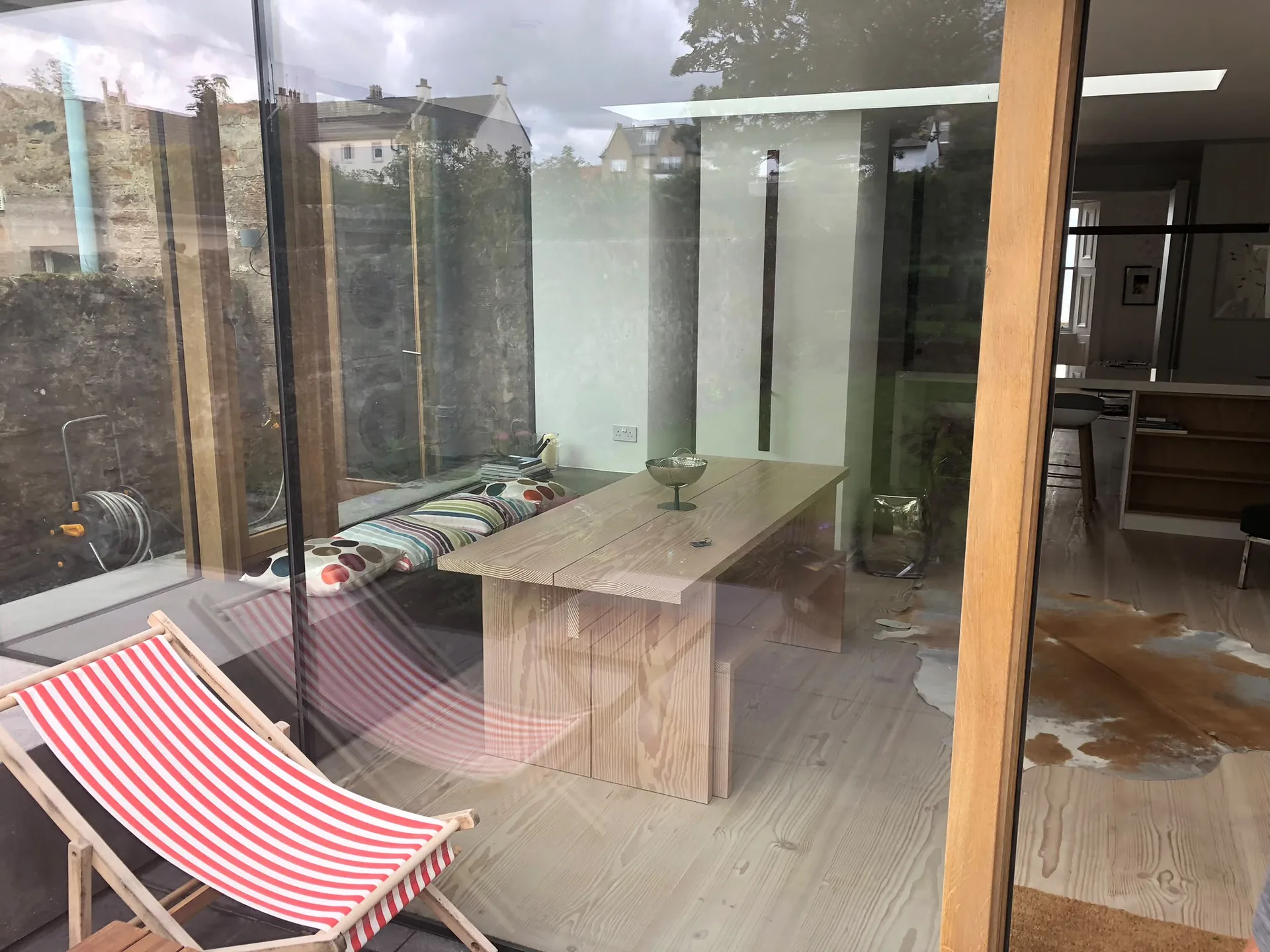 Garden room with wooden flooring, fitted wooden table and frameless glass walls