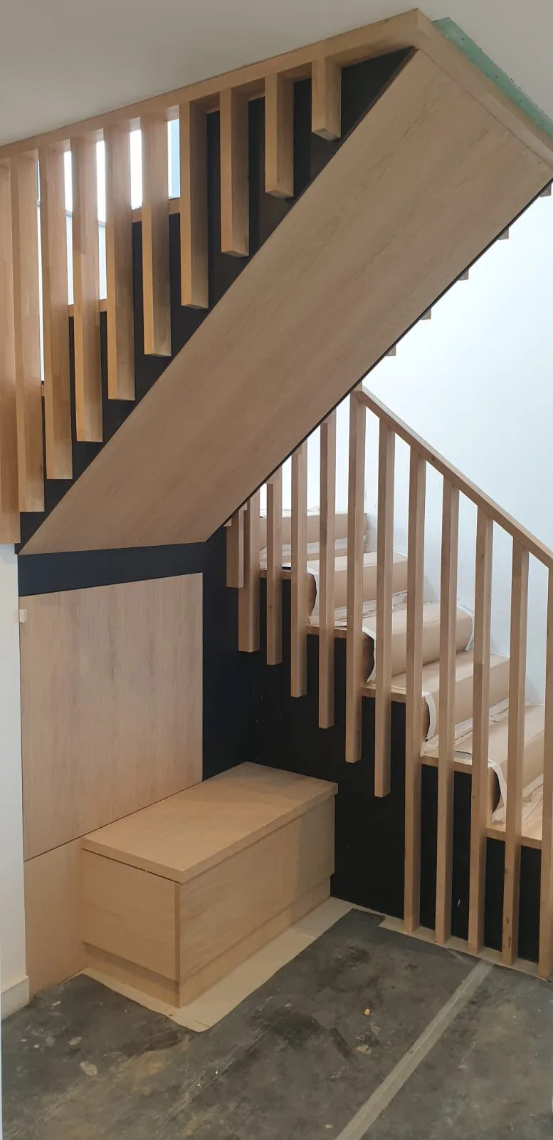 Bespoke wooden staircase with geometric lattice handrail design and integrated storage drawer in modern interior