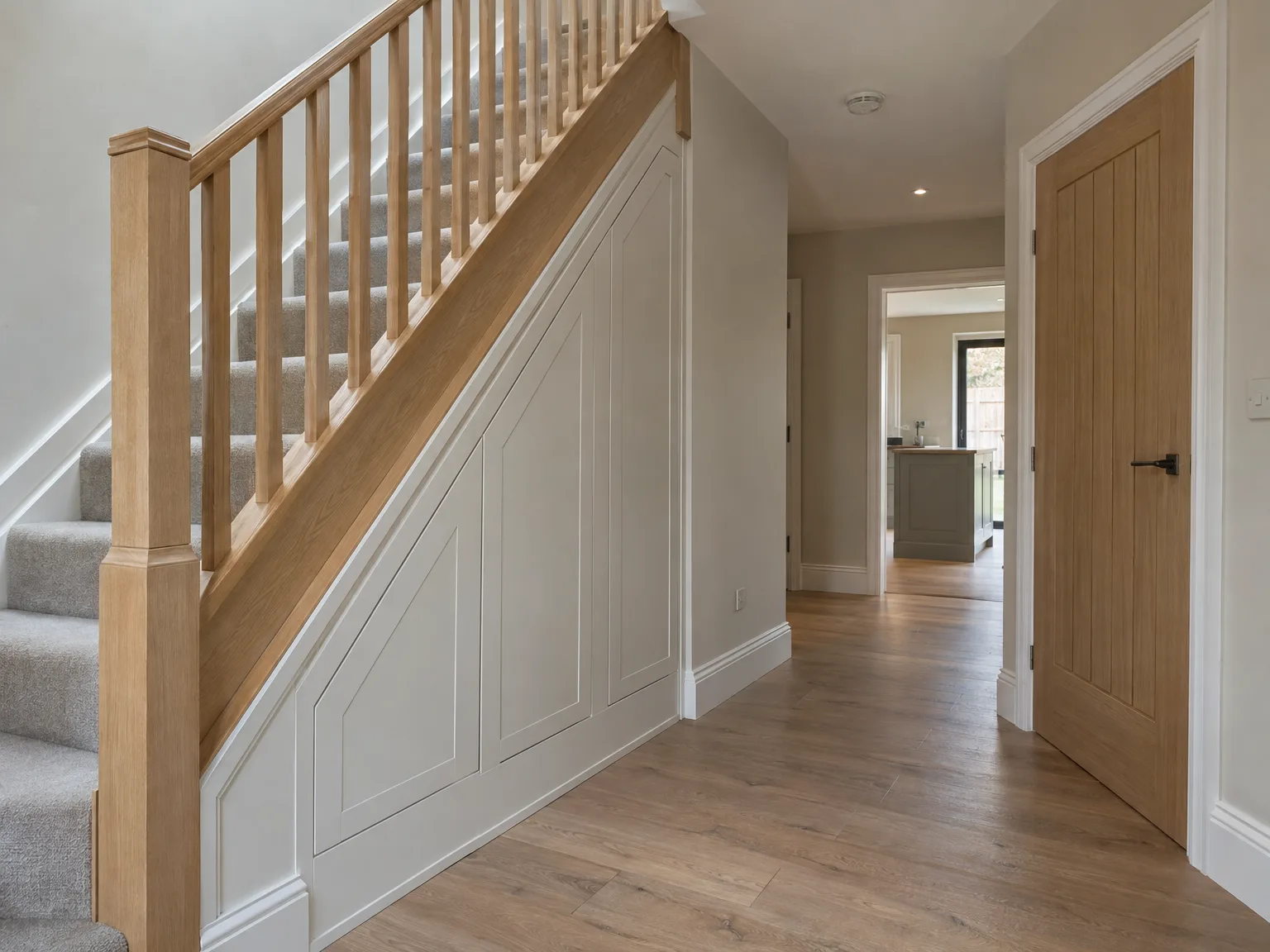Modern hallway with bespoke wooden staircase, white panelling and fitted timber doors