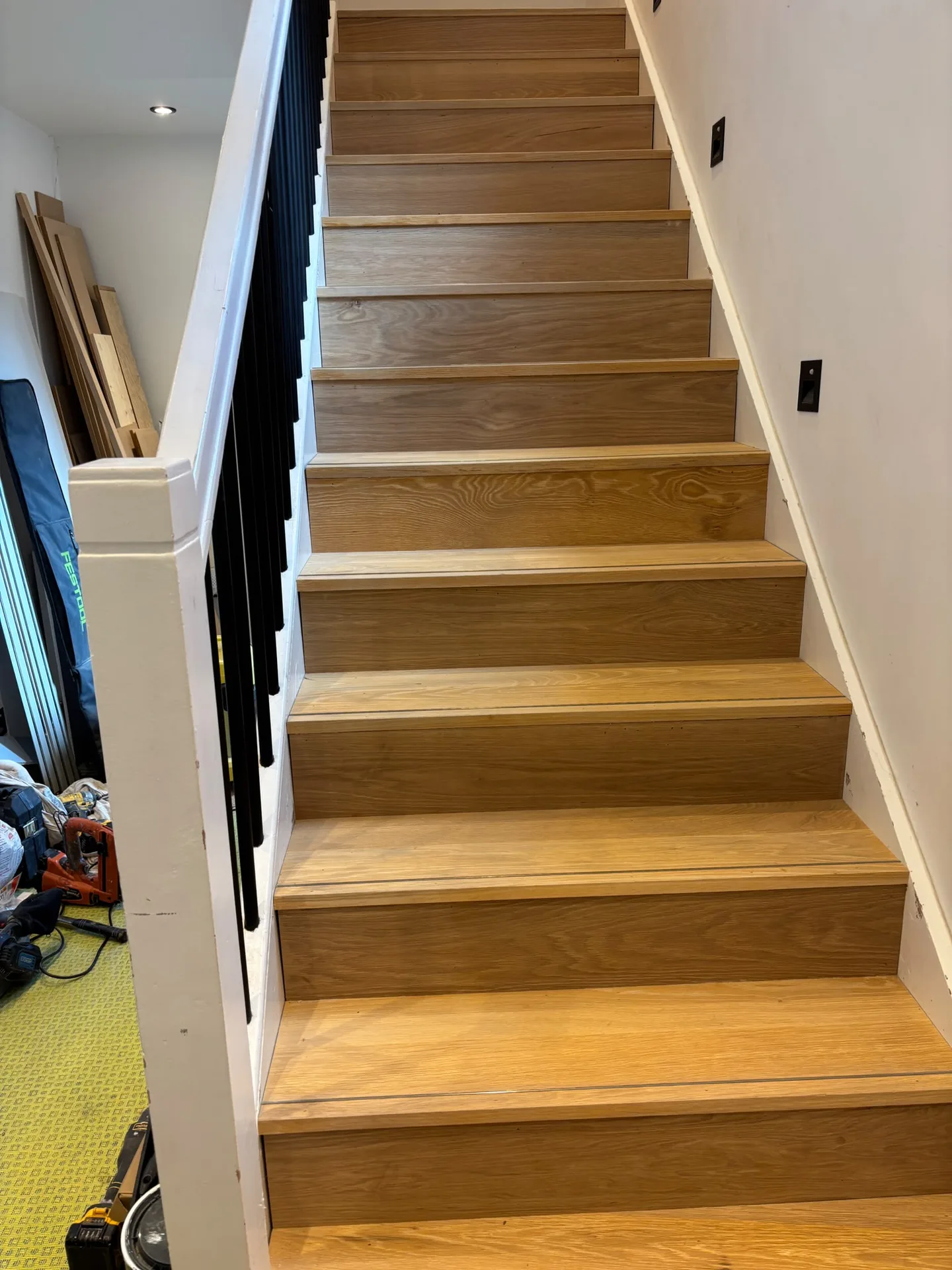 Custom wooden staircase with natural oak finish and metal handrail in renovated interior space