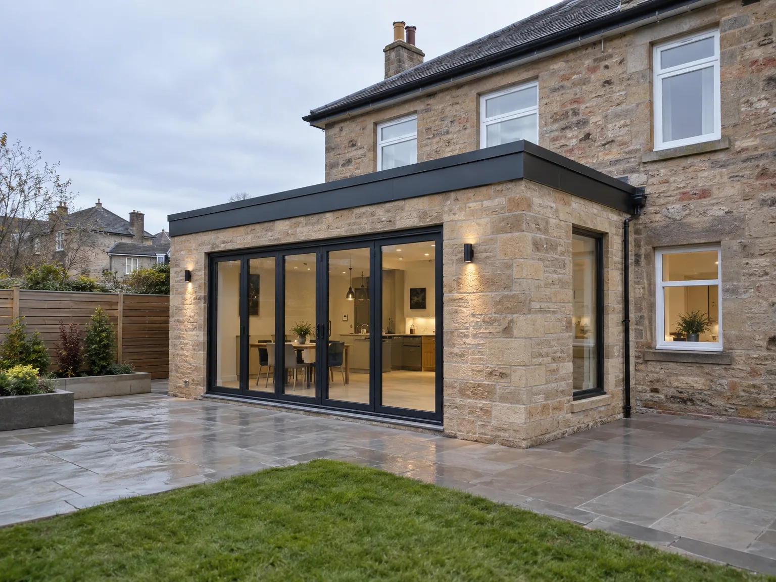 House extension with black-framed sliding doors and stone patio area