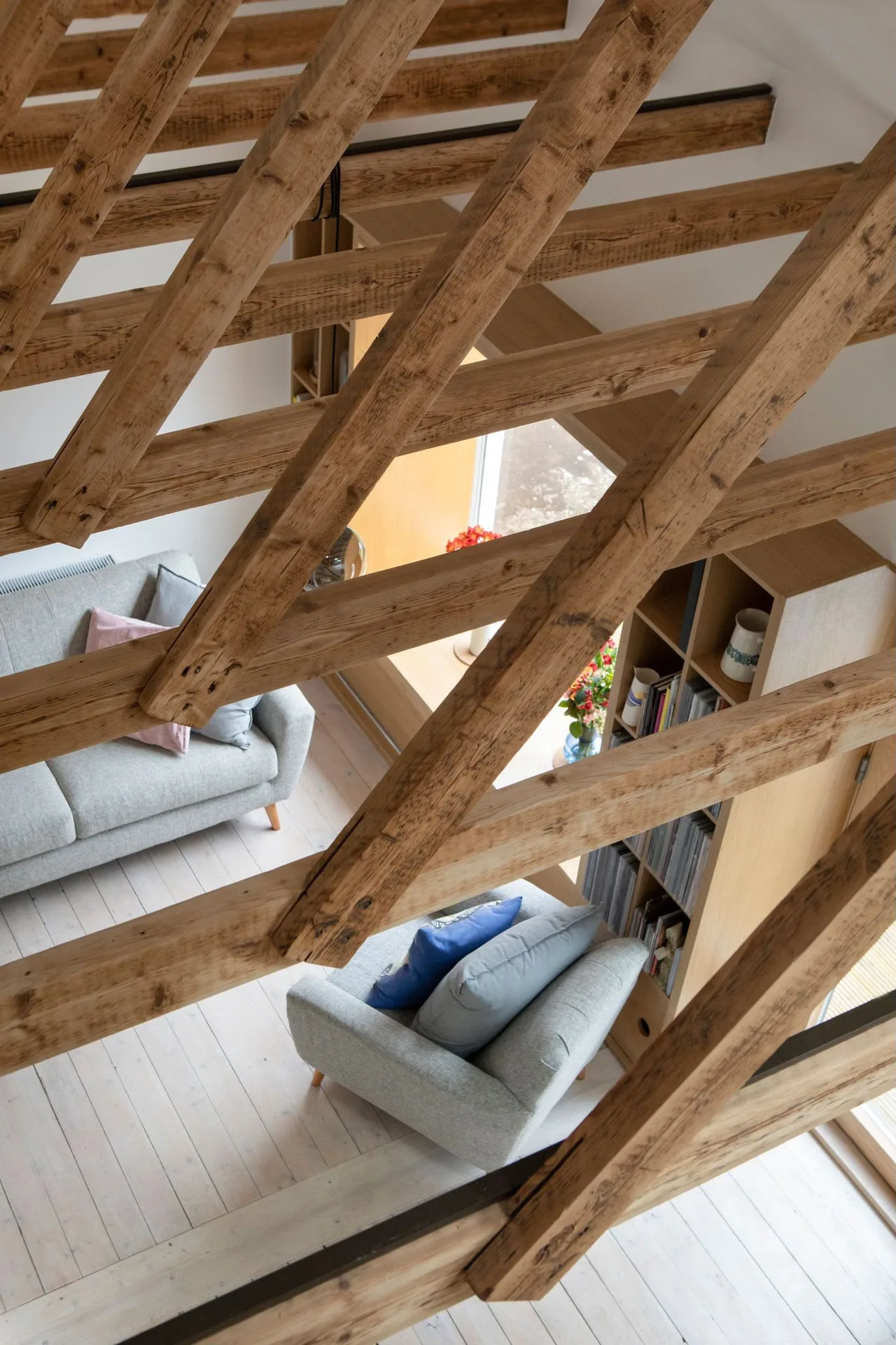 Loft conversion interior with exposed wooden beams, built-in shelving, and modern lounge seating area