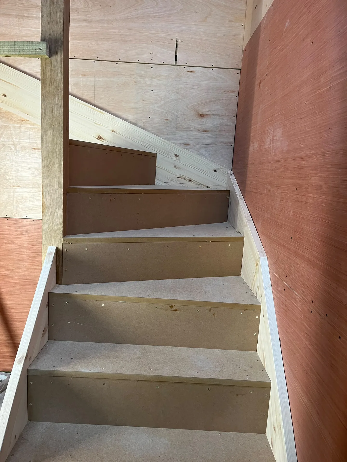 Wooden staircase under construction with brown treads in residential renovation project