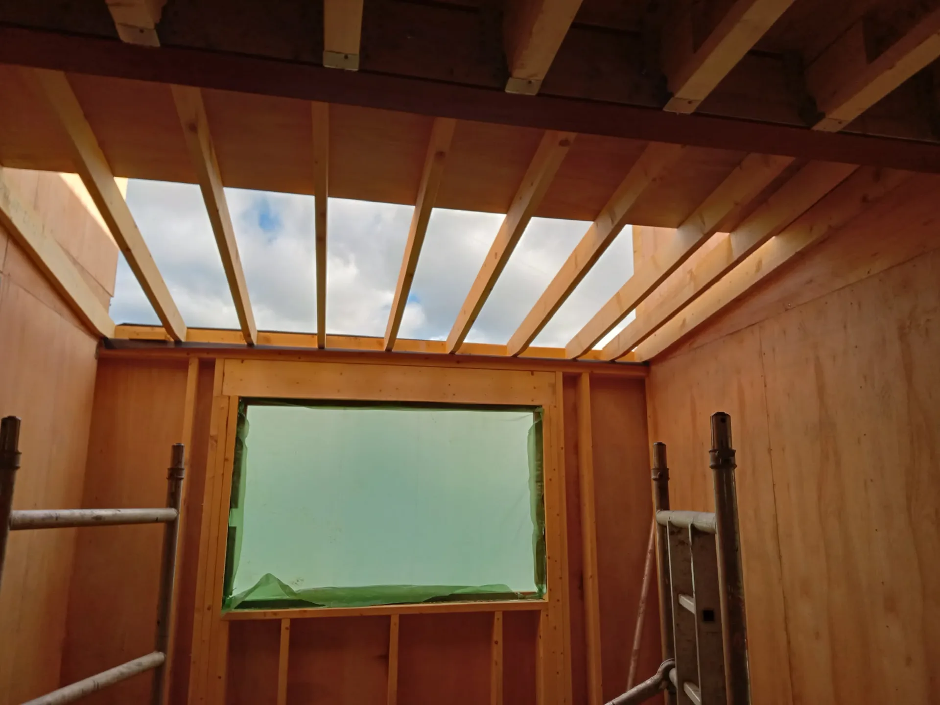 Timber structural frame with glazed roof and plastic window protection during construction