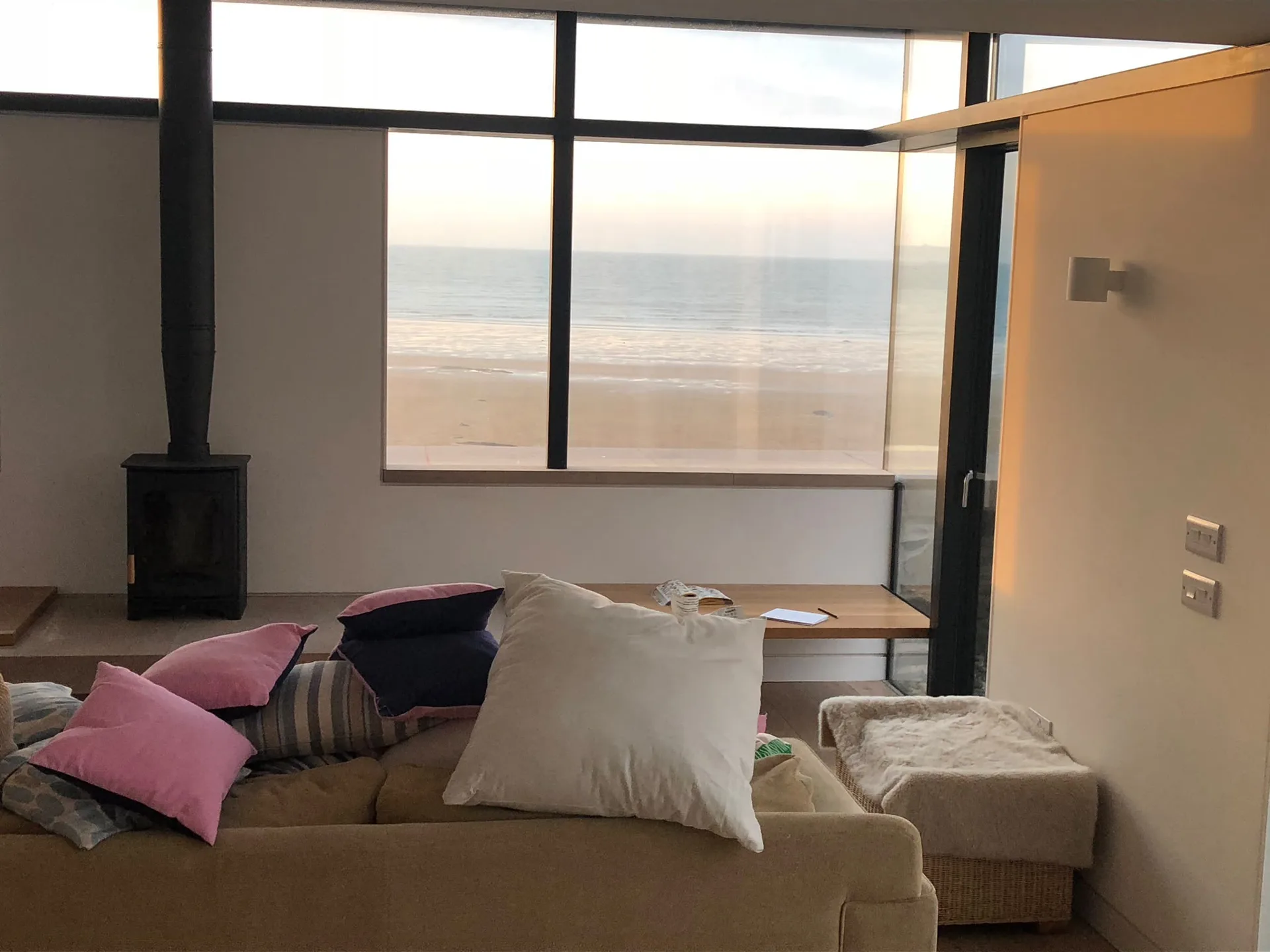 Modern coastal living space with panoramic sea view windows and contemporary fireplace