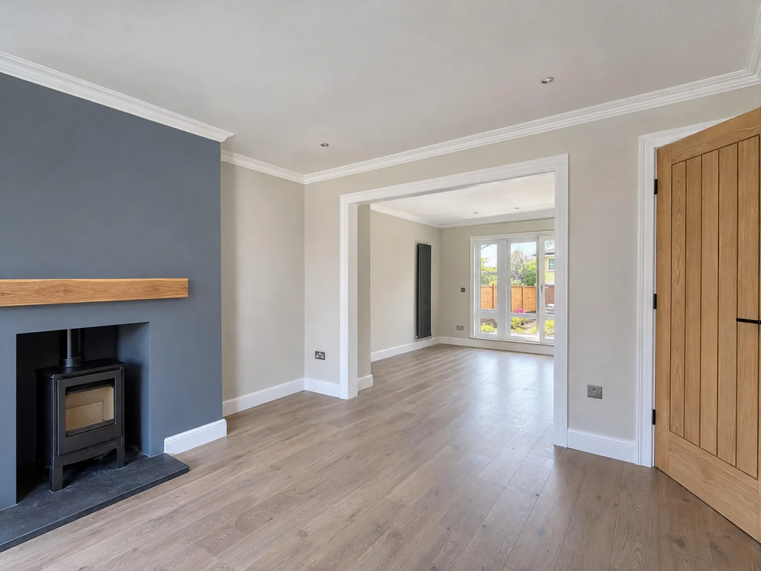 Modern interior with fireplace and wooden mantelpiece, light wood flooring, oak doors and painted walls