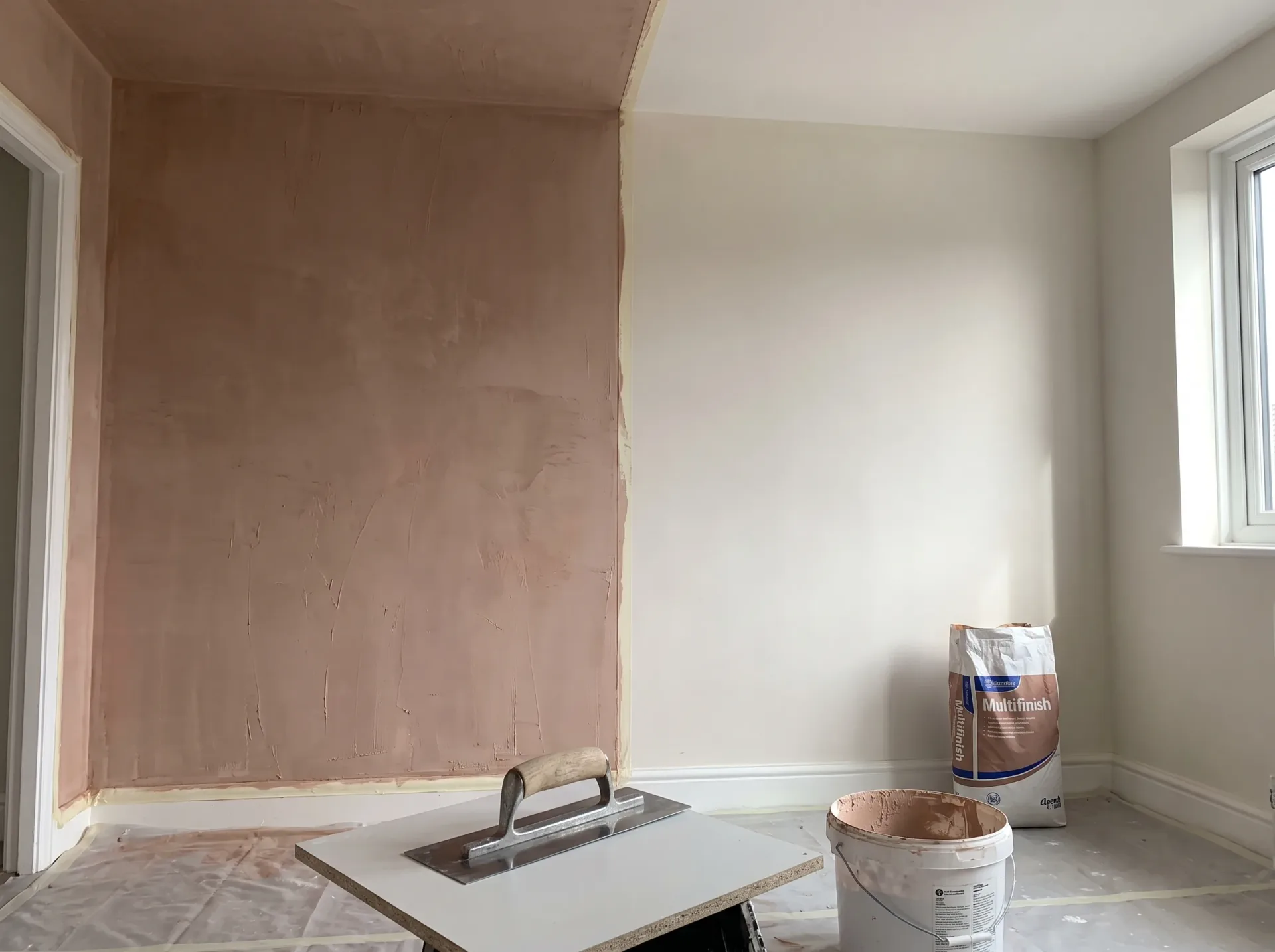Interior wall plastering in progress showing prepared surfaces and compound application materials