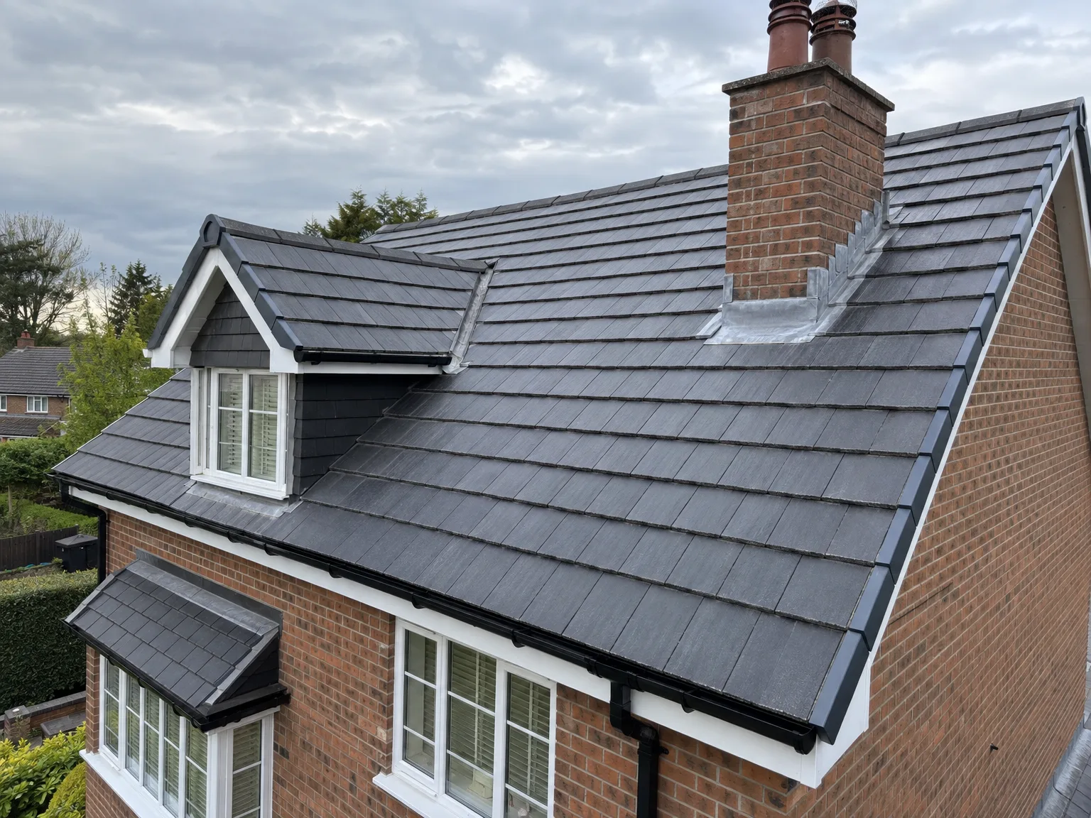 New slate roof with dormer window and clay chimneys on brick home