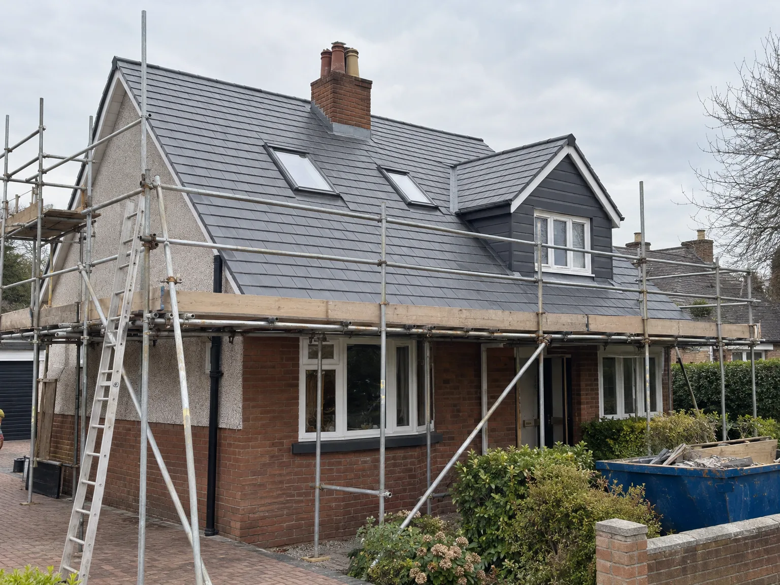 New roof installation with grey tiles, skylight windows and metal scaffolding during house renovation