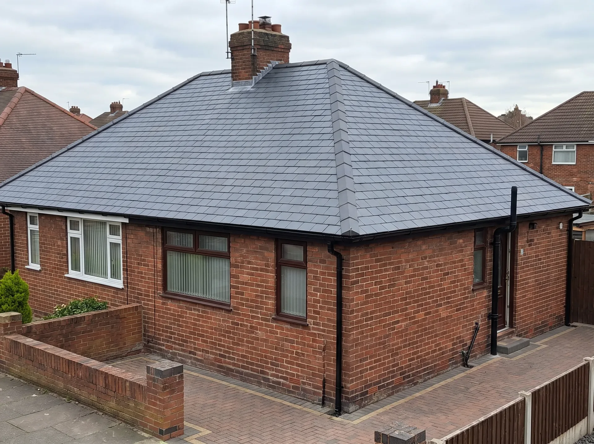 Modern slate-grey roof on red brick house extension with patio forecourt