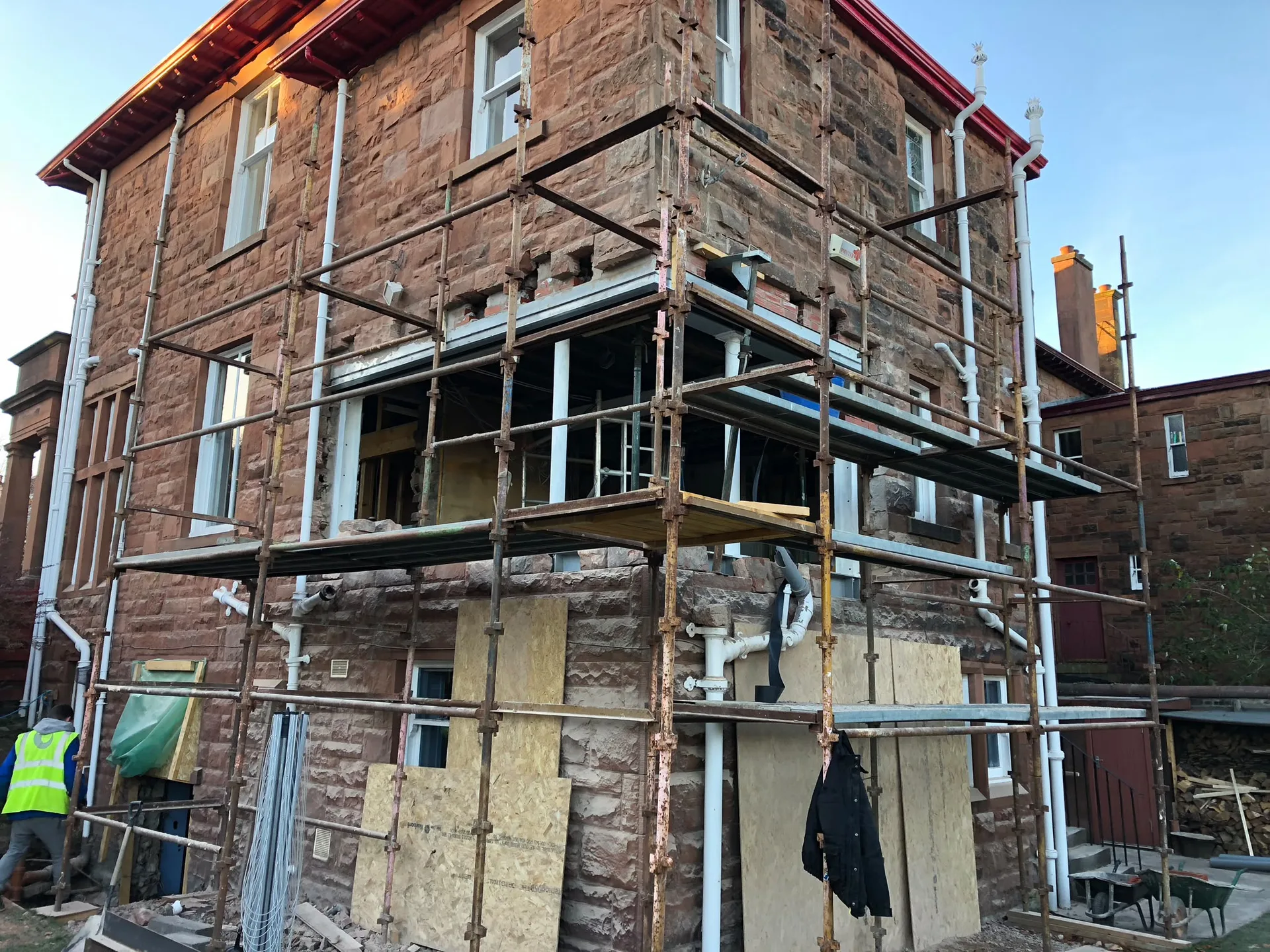 Property refurbishment of historic stone house with metal scaffolding, window boarding and construction work in progress