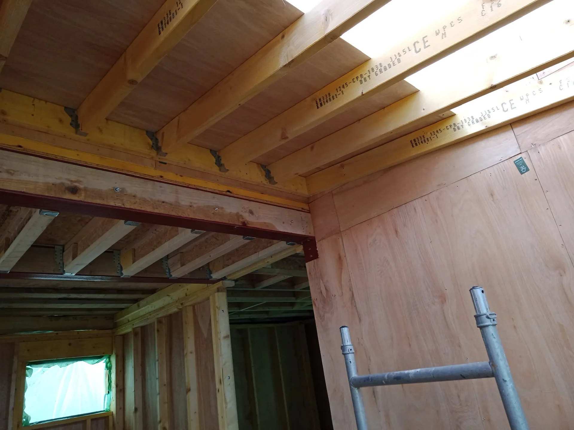 Wooden structural framework and floor joists during building construction with protective membrane insulation visible