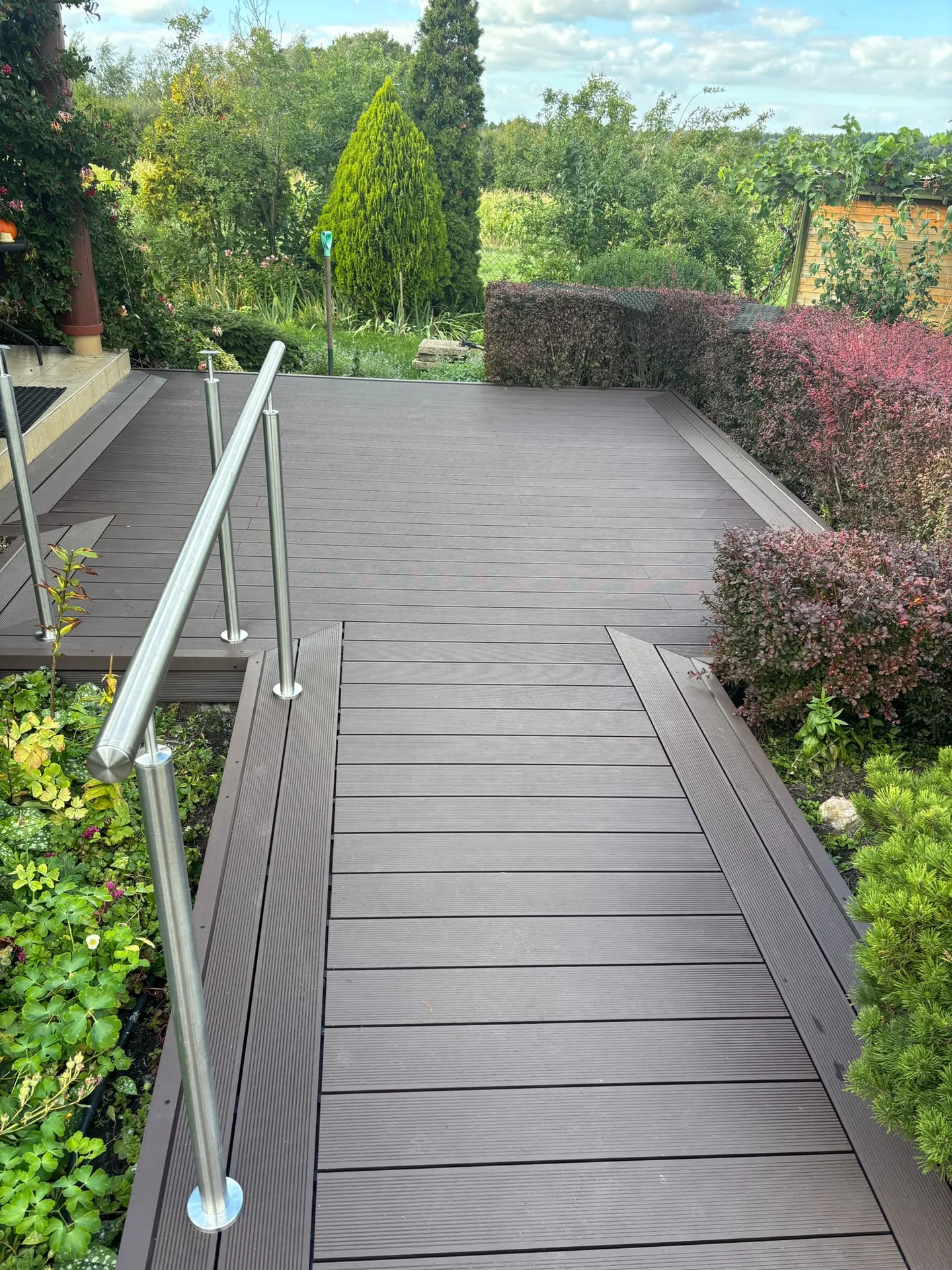 Modern timber decking with metal handrails and landscaped garden borders